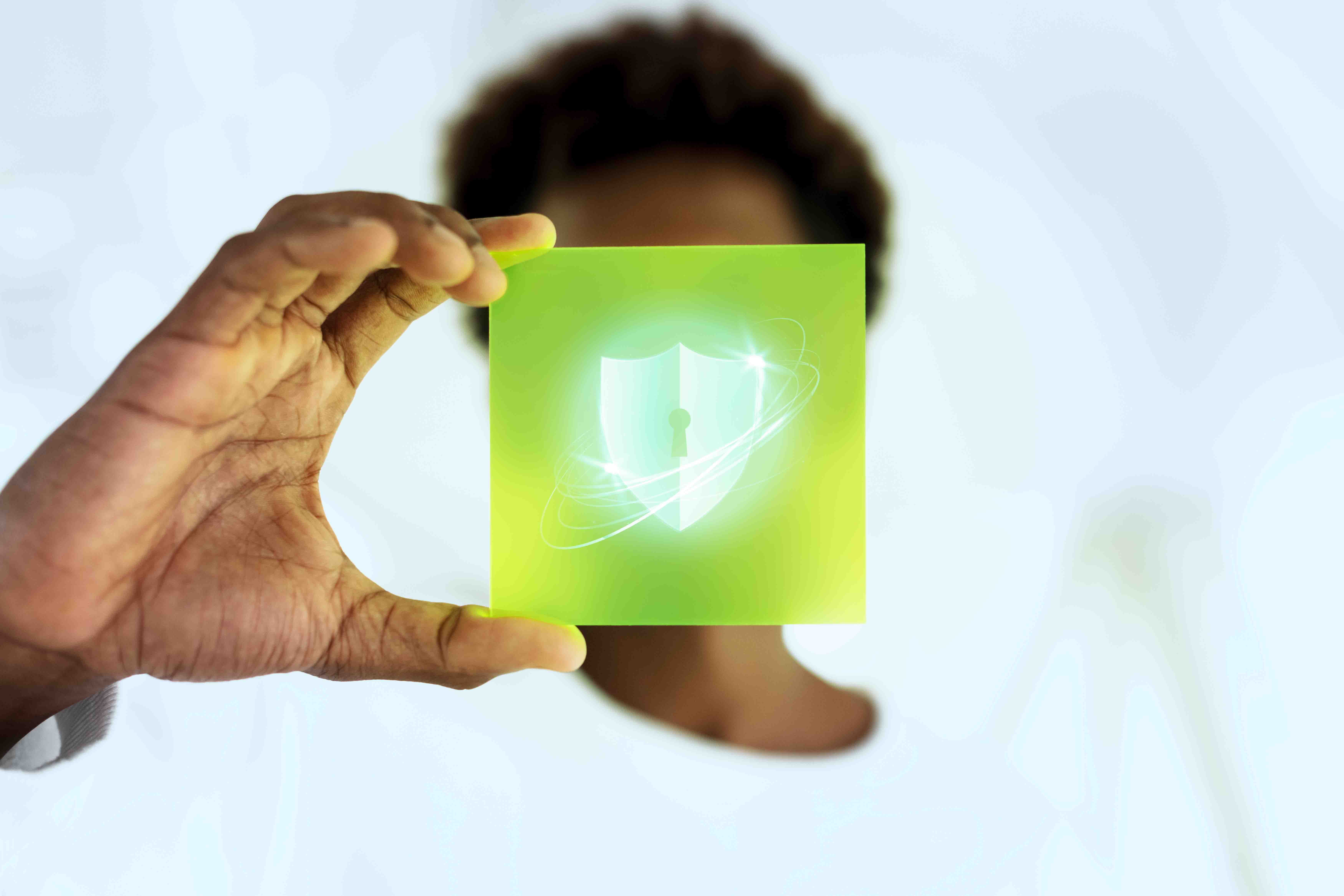 Women holding up a lime green square with a shield and lock hologram