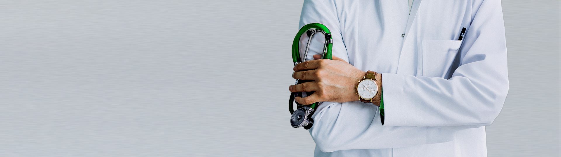 Doctor crossing arms holding green stethescope